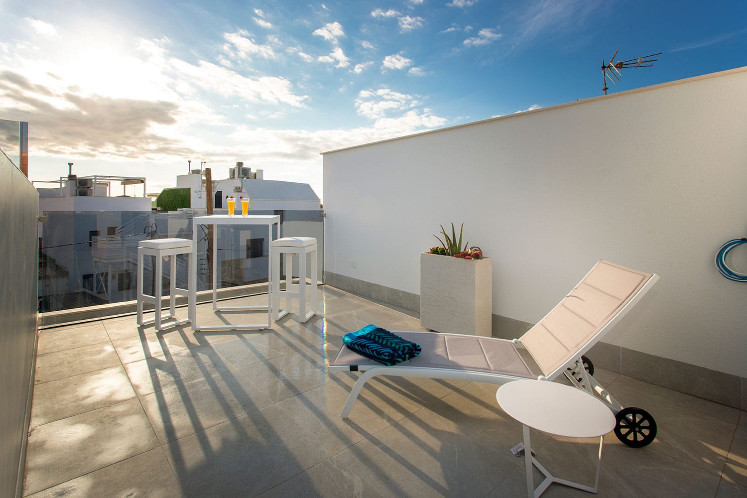 solarium con tumbonas y mesitas en la terraza de la vivienda